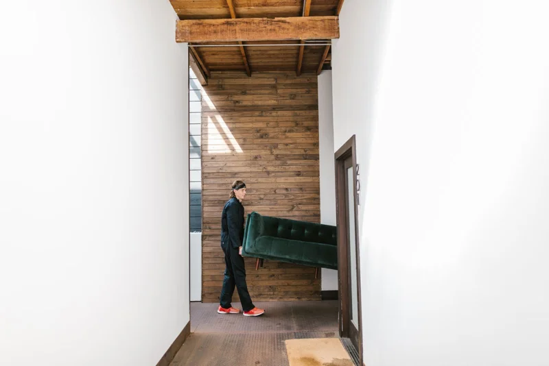 Un homme porte un fauteuil dans un couloir étroit